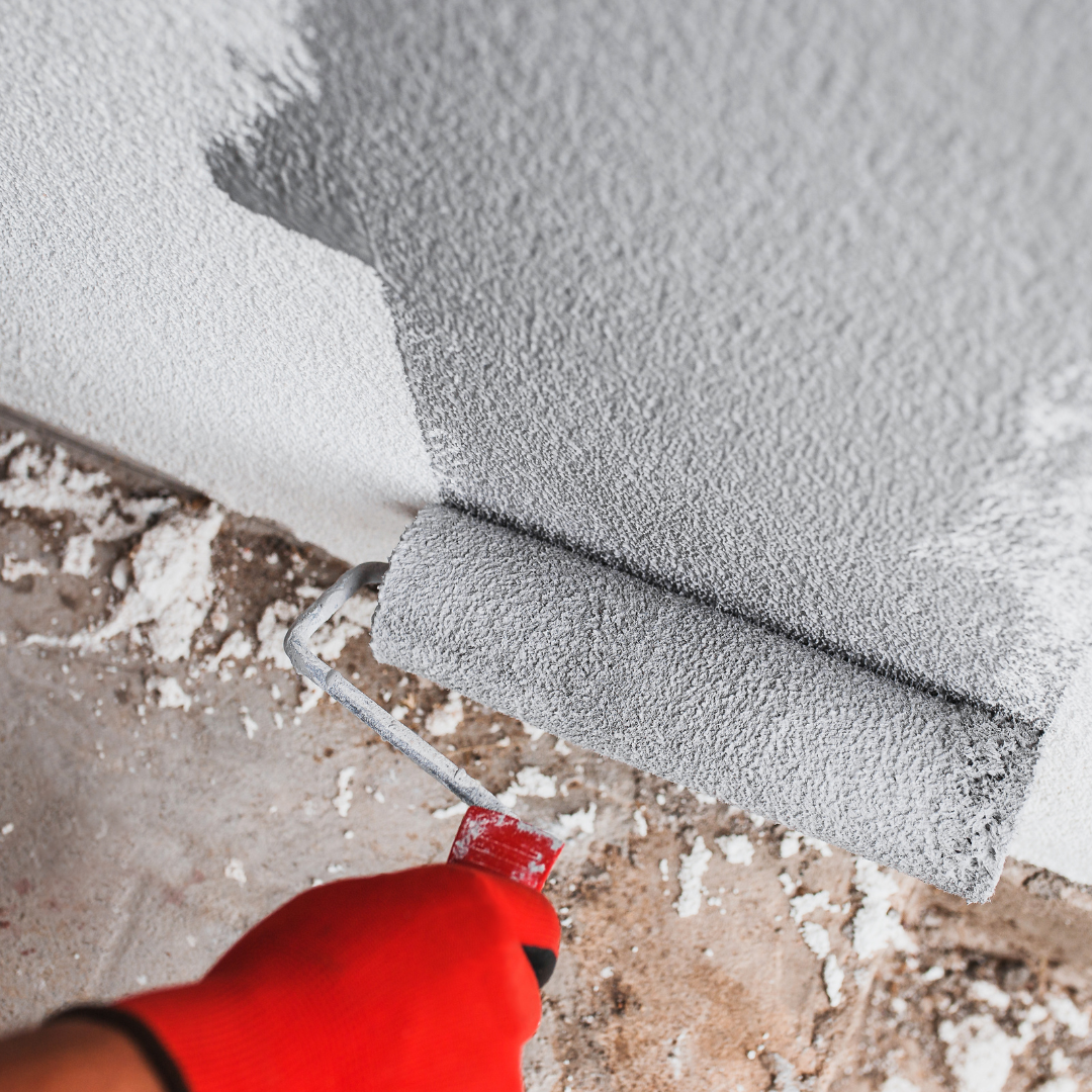 Paint roller applying grey paint to a wall